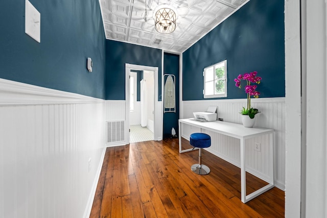 interior space with an ornate ceiling, wainscoting, visible vents, and wood finished floors