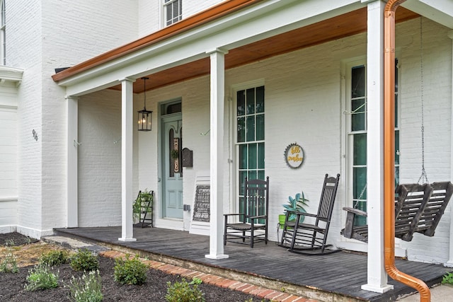 entrance to property featuring covered porch and brick siding