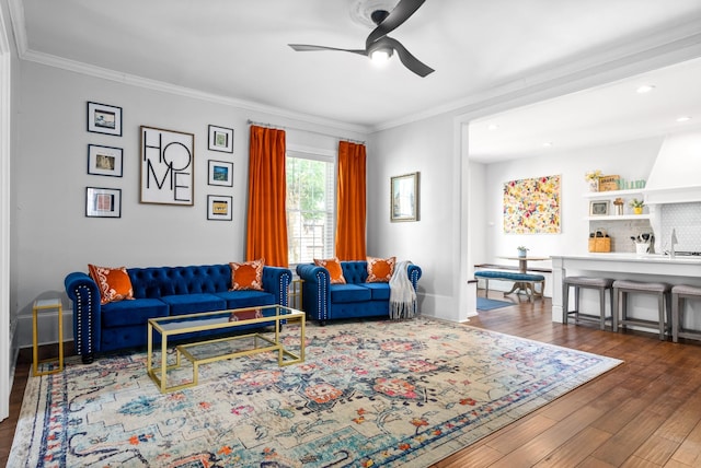 living area featuring ceiling fan, baseboards, dark wood finished floors, and crown molding