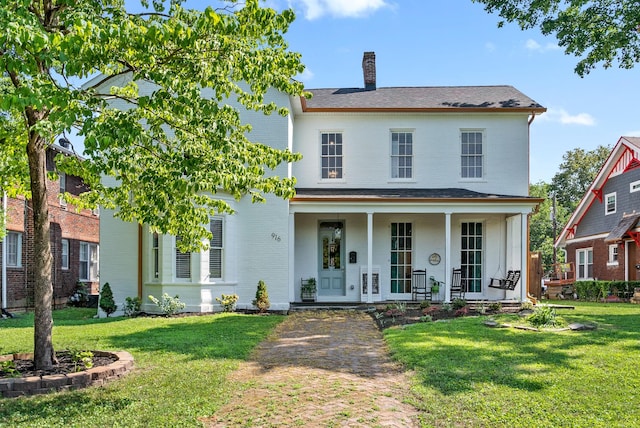 view of front of property featuring a porch, brick siding, a chimney, and a front lawn