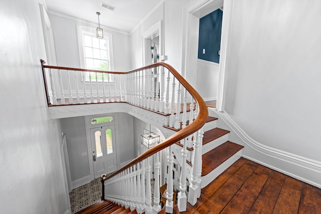 stairs with baseboards, visible vents, a towering ceiling, wood finished floors, and crown molding