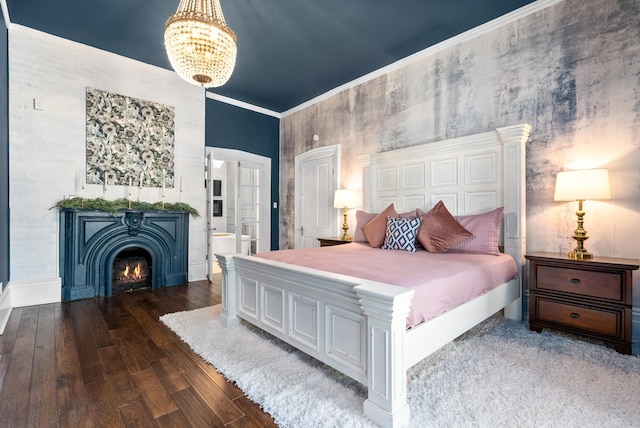 bedroom featuring a chandelier, a lit fireplace, dark wood-style floors, ensuite bath, and crown molding