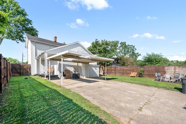 back of house featuring a carport, a lawn, concrete driveway, and a fenced backyard