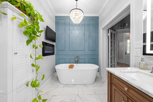 bathroom with marble finish floor, crown molding, a soaking tub, vanity, and baseboards