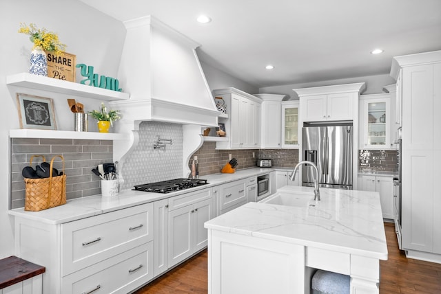 kitchen featuring open shelves, stainless steel fridge, glass insert cabinets, and white cabinets