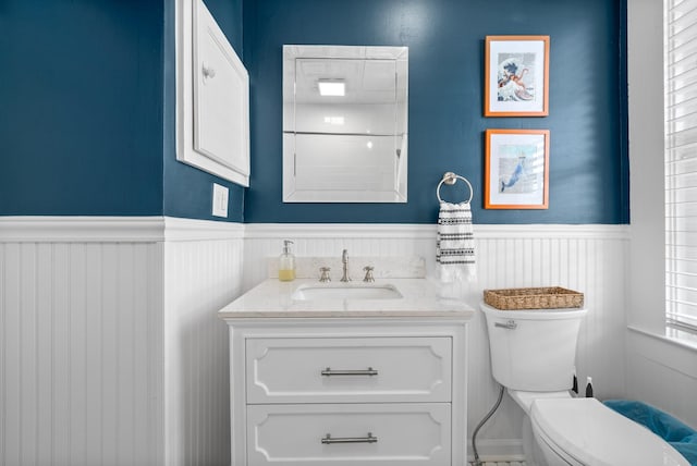 bathroom with wainscoting, vanity, and toilet