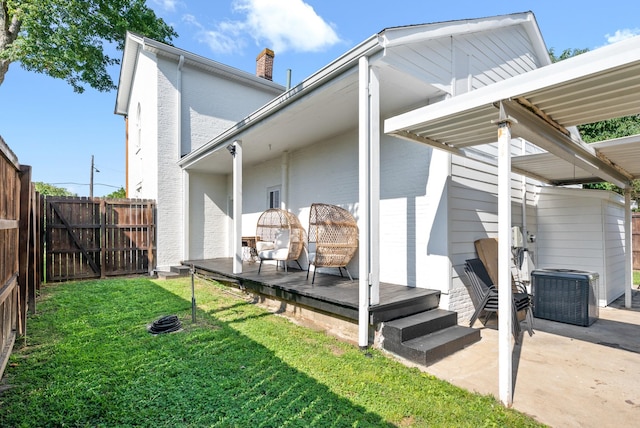 back of house with central AC unit, a fenced backyard, a chimney, a yard, and a patio area