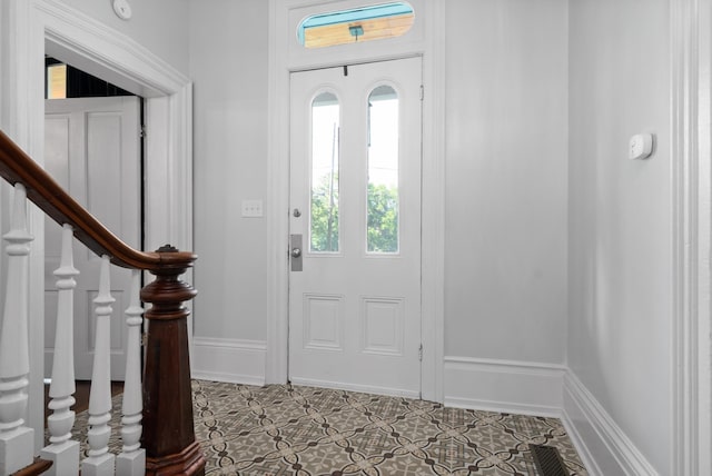 entrance foyer with light tile patterned floors, visible vents, baseboards, and stairs