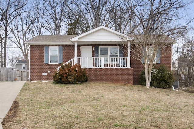 view of front of property featuring a front yard, covered porch, brick siding, and cooling unit