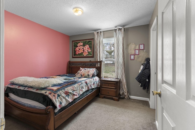 bedroom featuring light colored carpet, a textured ceiling, and baseboards