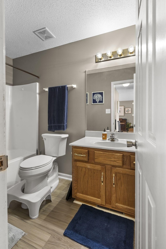 full bath featuring visible vents, toilet, a textured ceiling, vanity, and wood finished floors