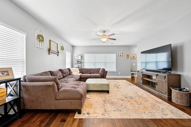 living area featuring dark wood-style flooring, a ceiling fan, and baseboards