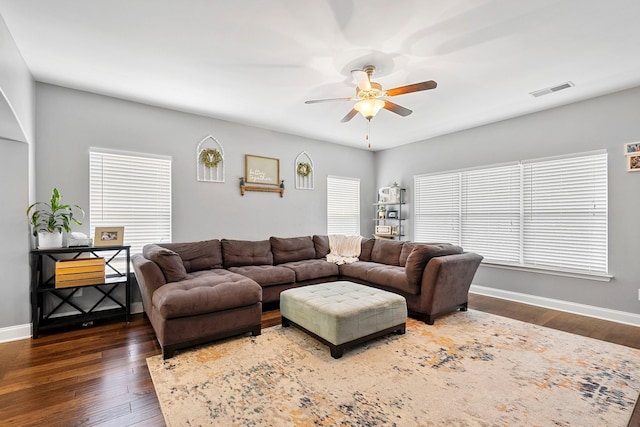 living area featuring a ceiling fan, dark wood finished floors, visible vents, and baseboards