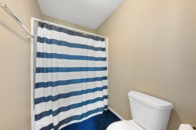 bathroom featuring toilet and curtained shower