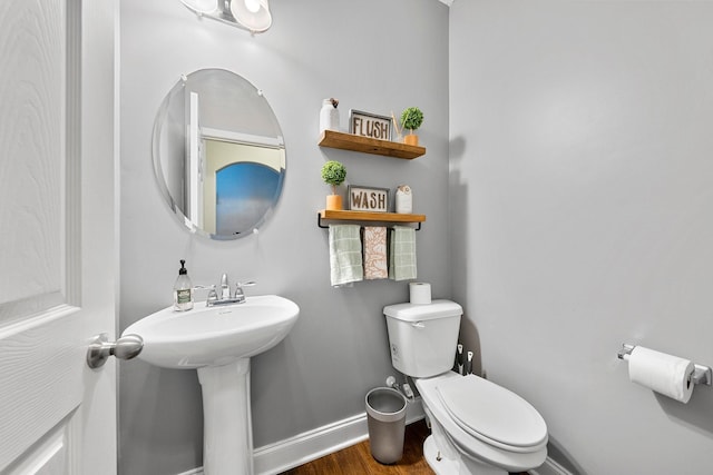 bathroom with baseboards, a sink, toilet, and wood finished floors