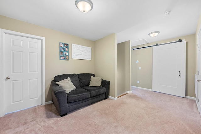 sitting room with baseboards, a barn door, and light colored carpet