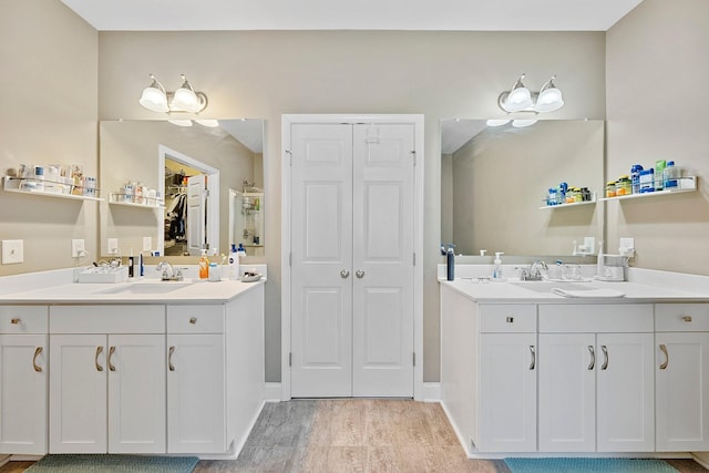 full bathroom with wood finished floors, two vanities, and a sink