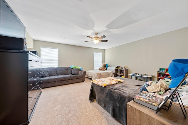 bedroom featuring a ceiling fan, light carpet, visible vents, and multiple windows