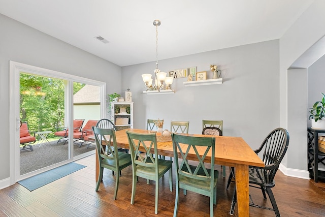 dining room featuring baseboards, visible vents, a chandelier, and wood finished floors