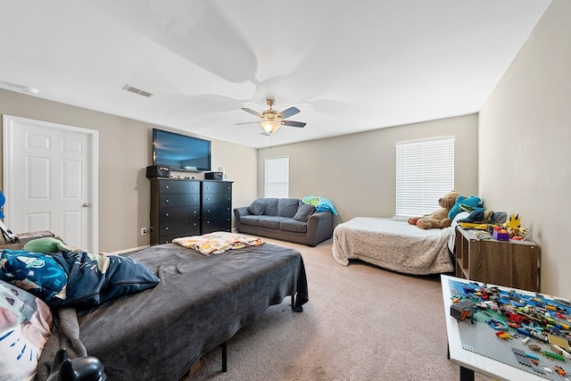 carpeted bedroom with a ceiling fan and visible vents