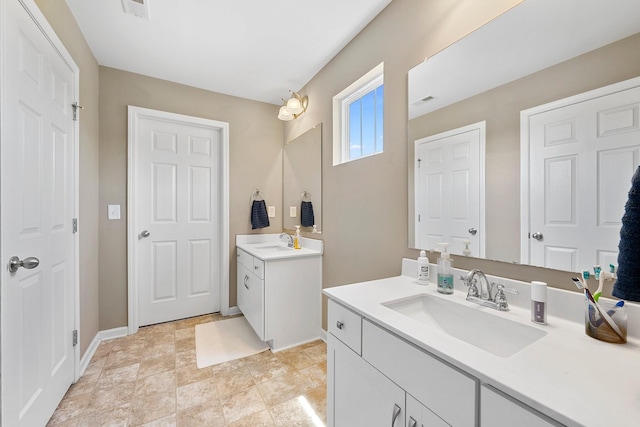 bathroom featuring two vanities, a sink, visible vents, and baseboards