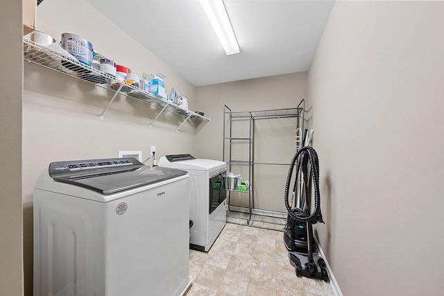 clothes washing area featuring laundry area, washer and clothes dryer, and baseboards