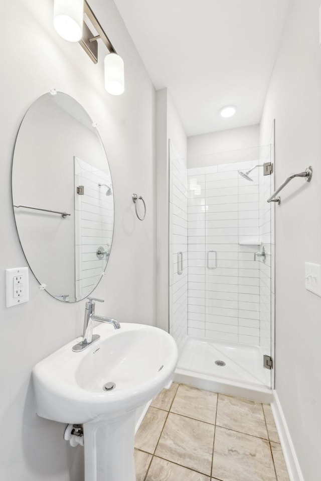 full bath featuring a stall shower, baseboards, and a sink