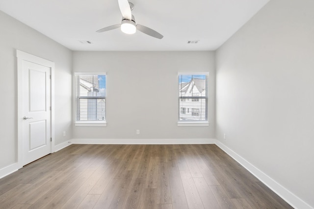 unfurnished room featuring a ceiling fan, wood finished floors, visible vents, and baseboards