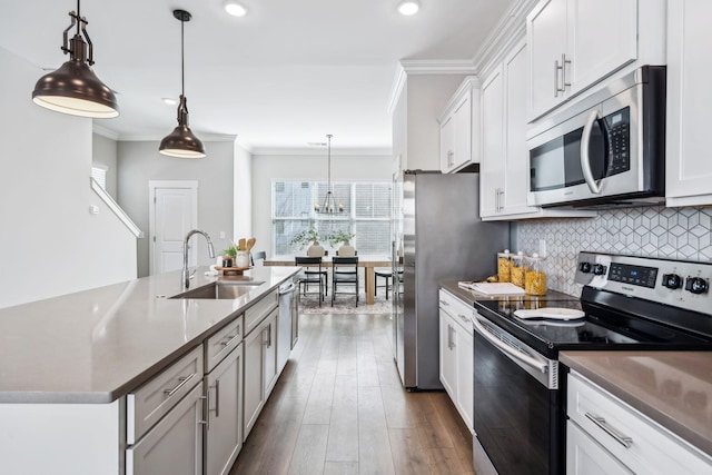 kitchen with appliances with stainless steel finishes, white cabinets, decorative light fixtures, and a sink