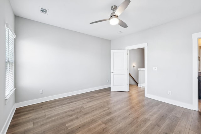 unfurnished bedroom featuring a ceiling fan, wood finished floors, visible vents, and baseboards