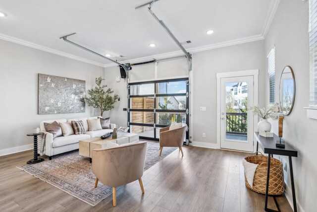 living room with a garage, wood finished floors, a wealth of natural light, and crown molding