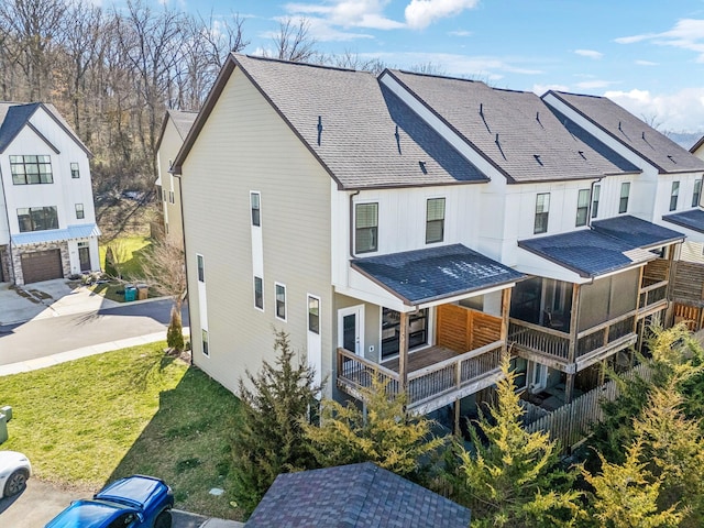 back of house with a shingled roof, a residential view, and a yard