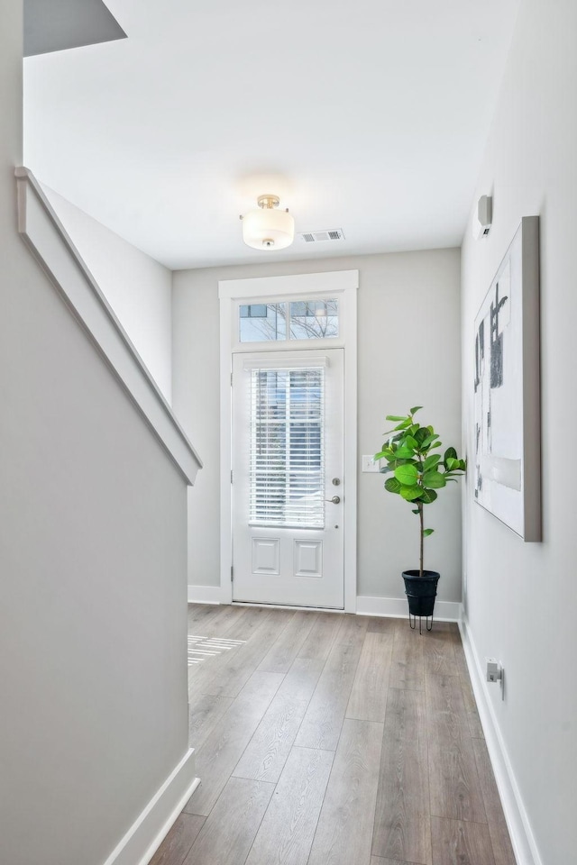 doorway with visible vents, baseboards, and wood finished floors