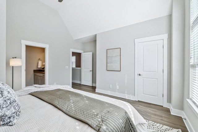 bedroom featuring high vaulted ceiling, baseboards, wood finished floors, and ensuite bathroom