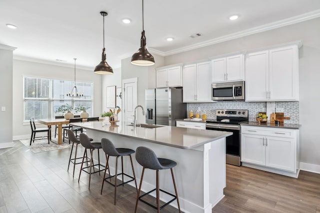 kitchen featuring an island with sink, white cabinetry, stainless steel appliances, and a sink