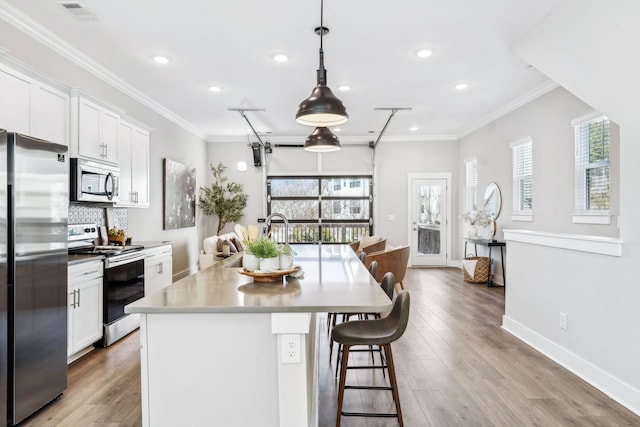 kitchen with appliances with stainless steel finishes, white cabinetry, hanging light fixtures, and visible vents