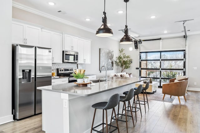 kitchen featuring white cabinetry, a center island with sink, appliances with stainless steel finishes, and a sink