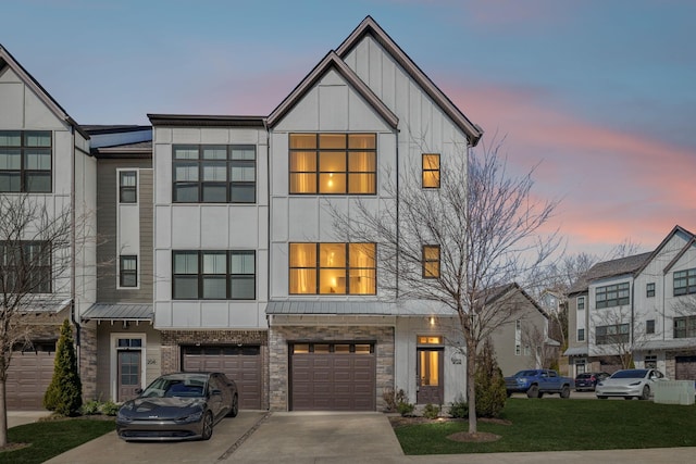 townhome / multi-family property featuring driveway, metal roof, an attached garage, a standing seam roof, and board and batten siding