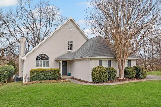 traditional-style home with stucco siding, a shingled roof, and a front yard