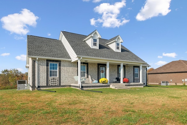 cape cod house featuring brick siding, a shingled roof, covered porch, central air condition unit, and a front yard