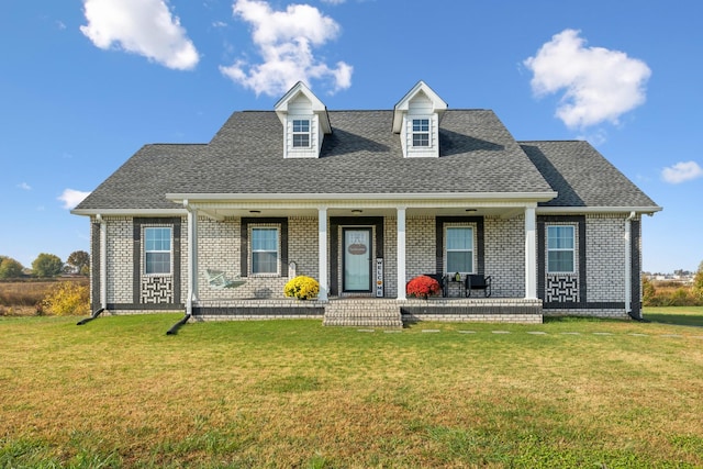 cape cod-style house featuring a shingled roof, a front lawn, a porch, and brick siding