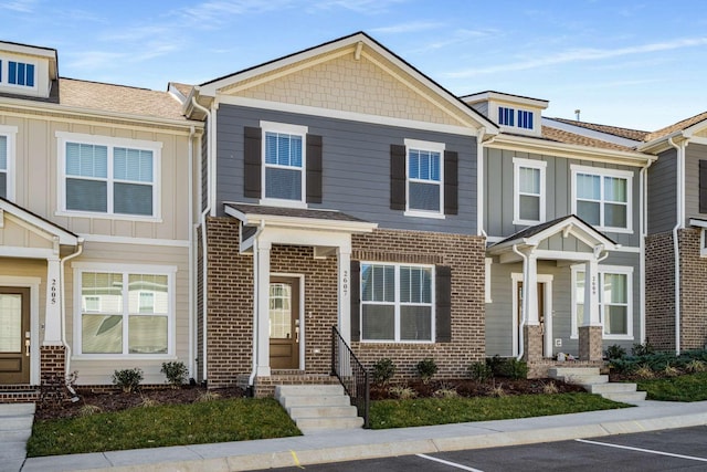 multi unit property featuring uncovered parking, board and batten siding, and brick siding