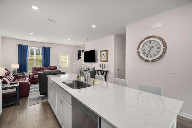 kitchen featuring dark wood-style floors, stainless steel dishwasher, open floor plan, white cabinetry, and a sink