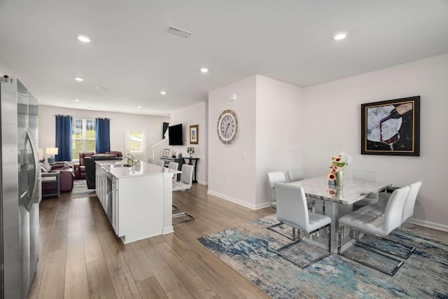 kitchen with a breakfast bar area, a sink, open floor plan, appliances with stainless steel finishes, and light wood-type flooring