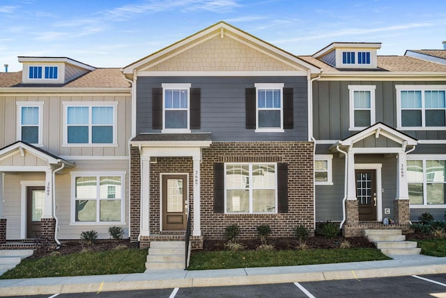 townhome / multi-family property featuring brick siding, board and batten siding, and a shingled roof