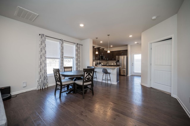 dining area with dark wood-style flooring, plenty of natural light, visible vents, and baseboards