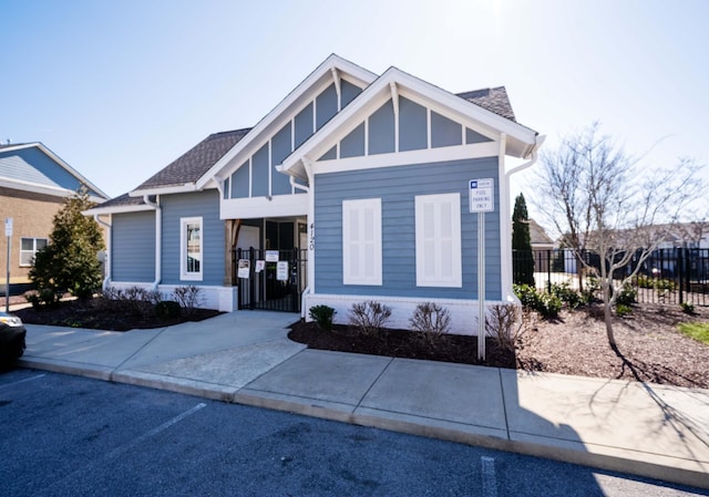 view of front of property with a shingled roof and fence