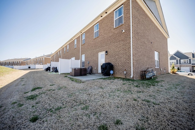 rear view of house with a patio, brick siding, fence, and a residential view