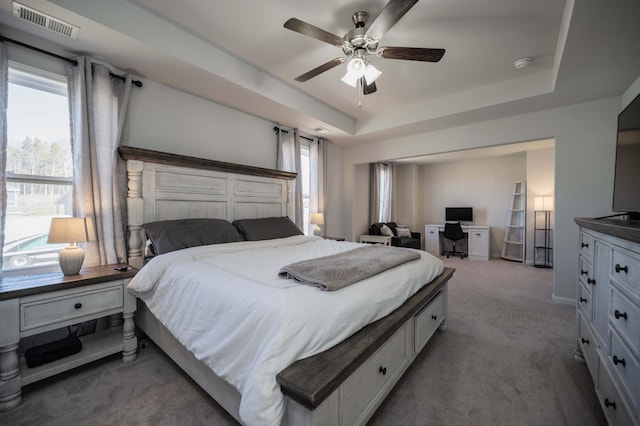 bedroom featuring ceiling fan, carpet floors, a raised ceiling, and visible vents