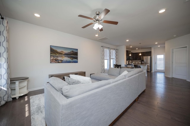 living area featuring a healthy amount of sunlight, baseboards, dark wood-style flooring, and recessed lighting